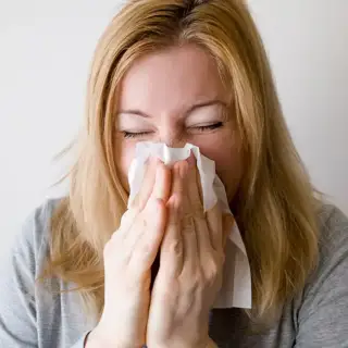 Woman blows her nose because of her winter allergies.