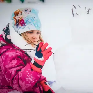 Two young children building a snowman.